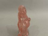 une petite figurine représentant un singe posée sur une surface blanche