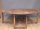 an oval oak table with turned legs and a wooden base