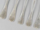 six silver spoons and a fork are lined up on a table
