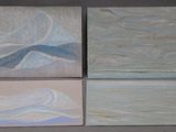 four paintings of different colors are displayed on a gray surface
