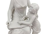 statue représentant une femme lisant un livre à un enfant assis sur un tabouret