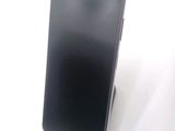 a black cell phone sitting on a stand on a white surface