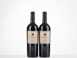 two bottles of red wine sitting on top of a table