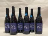 six bottles of wine are lined up on a white surface