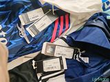 a pile of clothes with tags on them on a bed