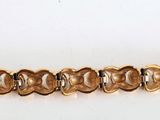a close up of a gold bracelet on a white surface