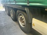 a green semi truck with a flat tire parked on the side of the road