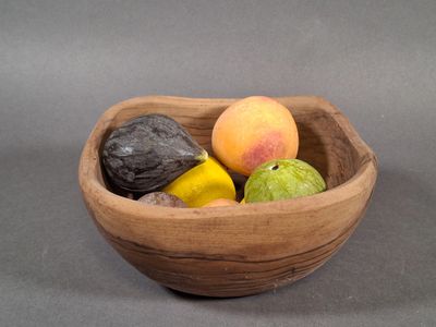 un saladier en bois rempli de fruits posé sur une table