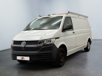 La camionnette blanche est garée dans une pièce au sol noir.