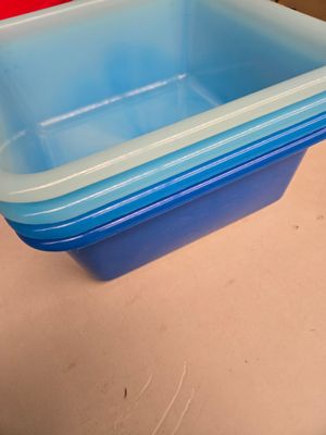 un récipient en plastique bleu posé sur une table à côté d'une chaise rouge