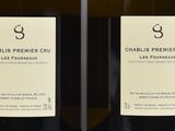 three bottles of white wine are lined up on a shelf