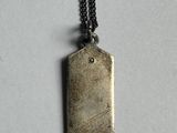 an image of a metal tag hanging from a chain on a white surface