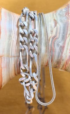 a person holding a bunch of silver bracelets on their arm