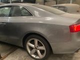une voiture argentée garée dans un garage, avec d'autres voitures en arrière-plan