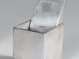 un récipient en argent muni d'un couvercle en argent, posé sur une surface blanche