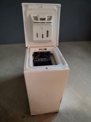un petit réfrigérateur blanc, la porte ouverte, posé à même le sol