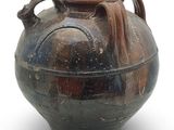 un grand vase muni d'une anse, posé sur une surface blanche