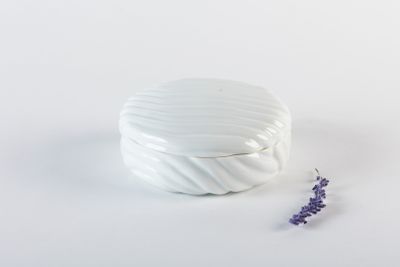 un récipient blanc avec une fleur violette à côté