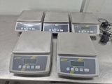 quatre balances électroniques posées sur une table dans une pièce