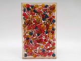 brightly colored lollipops in a clear box on a white surface