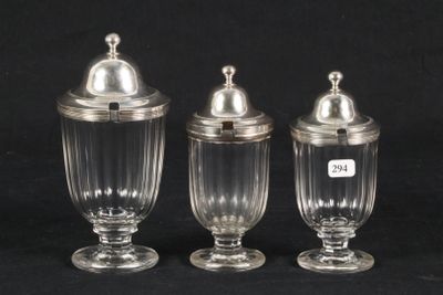 three clear glass jars with silver lids on a black background