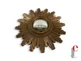 a gold sunburst mirror on a white wall