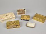 four small gold and mother of pearl boxes on a white surface