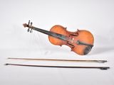 un vieux violon posé à côté d'un archet, sur une surface blanche