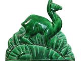 an image of a statue of a deer sitting on top of a lush green field