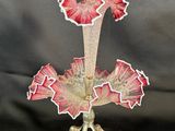 a glass vase with red flowers on it on a stand