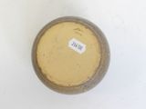 a brown vase with a label on it sitting on a white surface