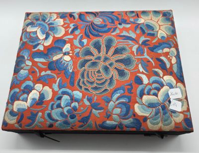 une image représentant une boîte rouge ornée de fleurs bleues et blanches