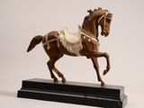 statue of a horse with a saddle on its back on a black base