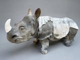 a sculpture of a rhino standing on a gray surface