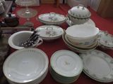 many plates and bowls sitting on a table with a red table cloth