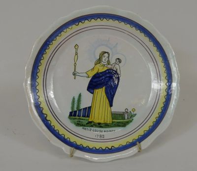 une assiette bleue et jaune sur laquelle est représentée une femme tenant un bébé dans ses bras
