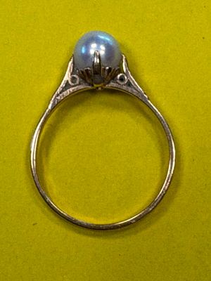 une bague en argent sertie d'une perle, sur un fond jaune
