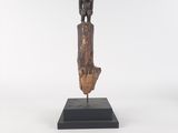 une statue en bois représentant une femme tenant un bébé dans ses bras, posée sur un socle noir