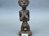 une vieille statue en bois représentant une femme tenant un bébé dans ses bras