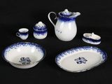 a blue and white table setting with a pitcher, bowl, cup, and saucer