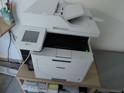 une imprimante blanche posée sur un bureau en bois