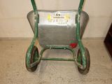 a small metal wheelbarrow with a green handle on the floor