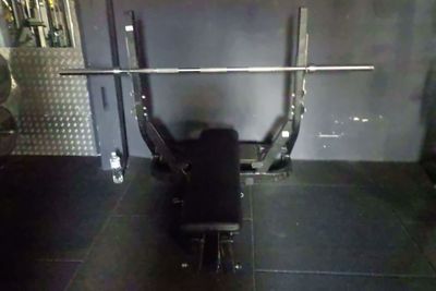 une photo d'une salle de sport avec un banc et une barre