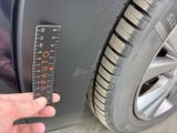 a hand that is holding a ruler next to a car