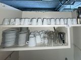 many plates and cups on the shelves in the kitchen