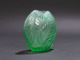 green glass vase sitting on top of a black surface