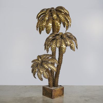 un palmier doré posé sur un socle en bois, sur fond blanc