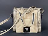 an image of a beige and black purse with a black and white strap
