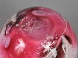 a glass ball that has a pink and white design on it