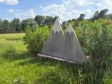 a cement triangle in the middle of a grassy field